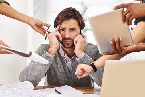Poor time management. A handsome businessman with colleagues requesting various things. istock/unsplash.